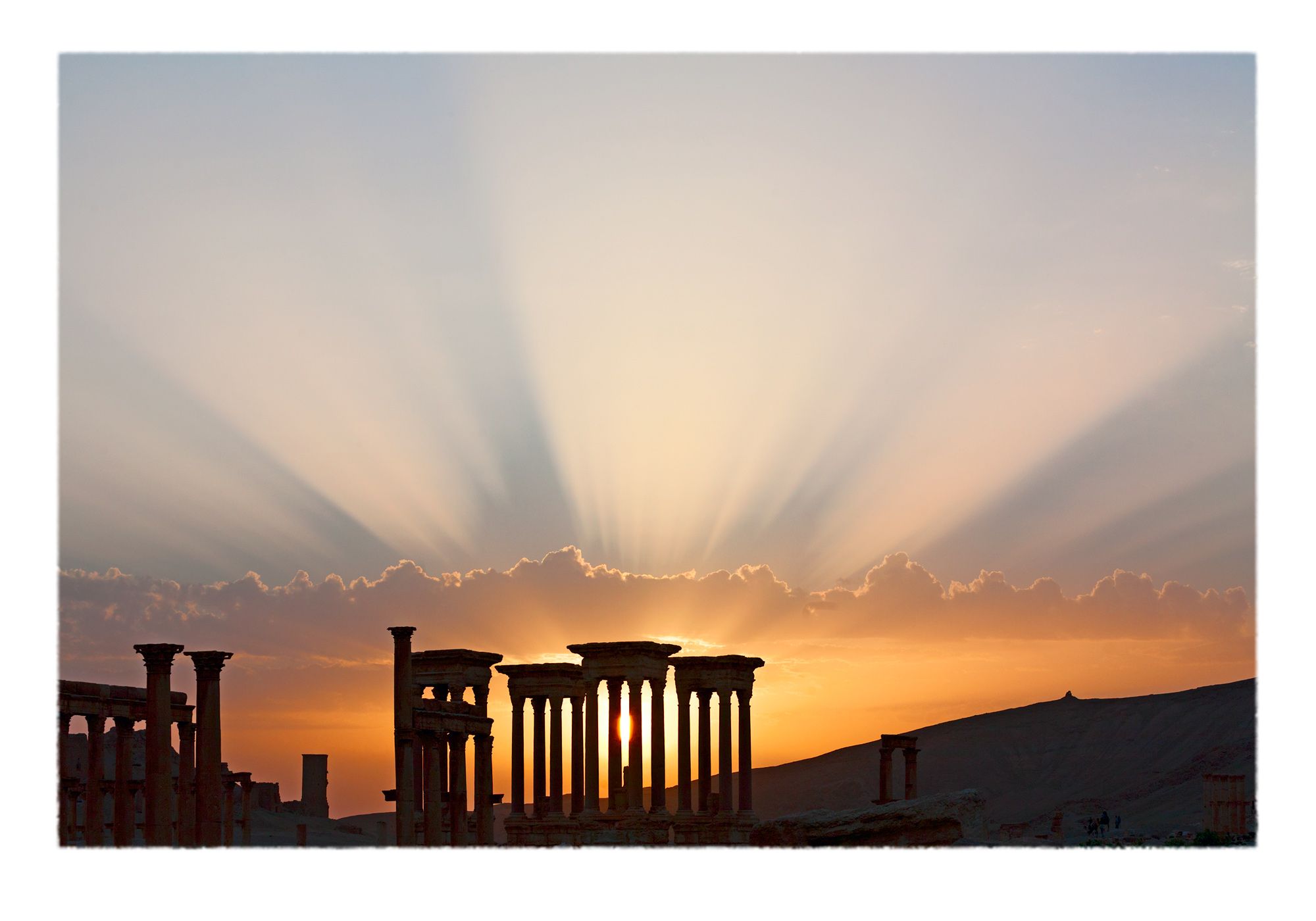 Radial spokes of sunset light over the Roman-era archaeological ruins of Palmyra, Syria